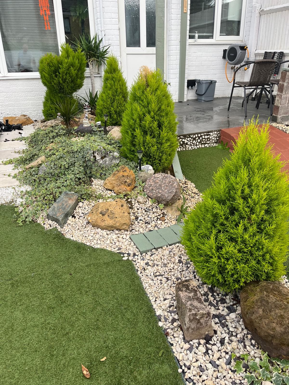A completed GNJ garden with green turf, a planted rockery and pale decorative gravel